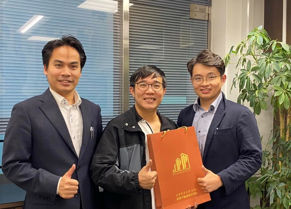 An Lac staff with a visitor holding an An Lac Real Estate gift bag at the Kita-ku office